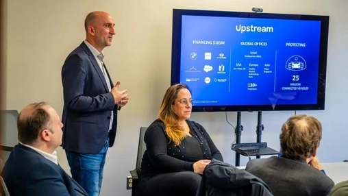 Presenter at a screen showing Upstream Security's company profile with financing and global office details