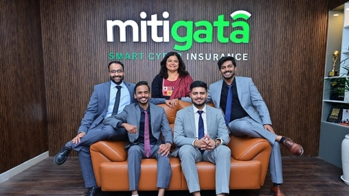Group of professionals posing together in front of the Mitigata Smart Cyber Insurance logo on a wooden wall