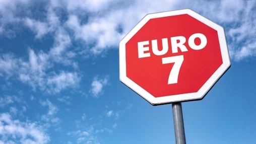 A red octagonal sign reading Euro 7 stands mounted on a tall metal pole against a bright blue summer sky