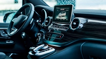Modern car interior with leather steering wheel, gear selector, and a central infotainment touchscreen