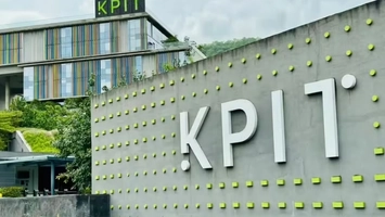 KPIT brand sign on a curved concrete facade with green dots, multi-storey building visible in the background